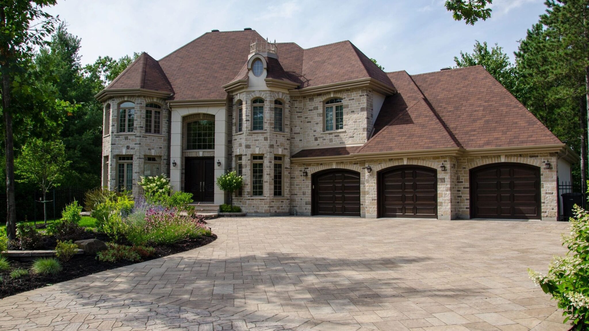 A large brick home with an attached 3-car garage and stone-paved entranceway and driveway.