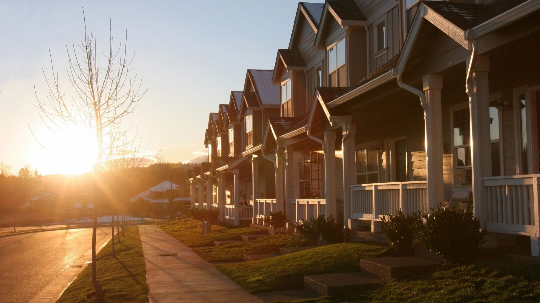 The sunsets on a row of newly built homes that all look alike on a suburban street.