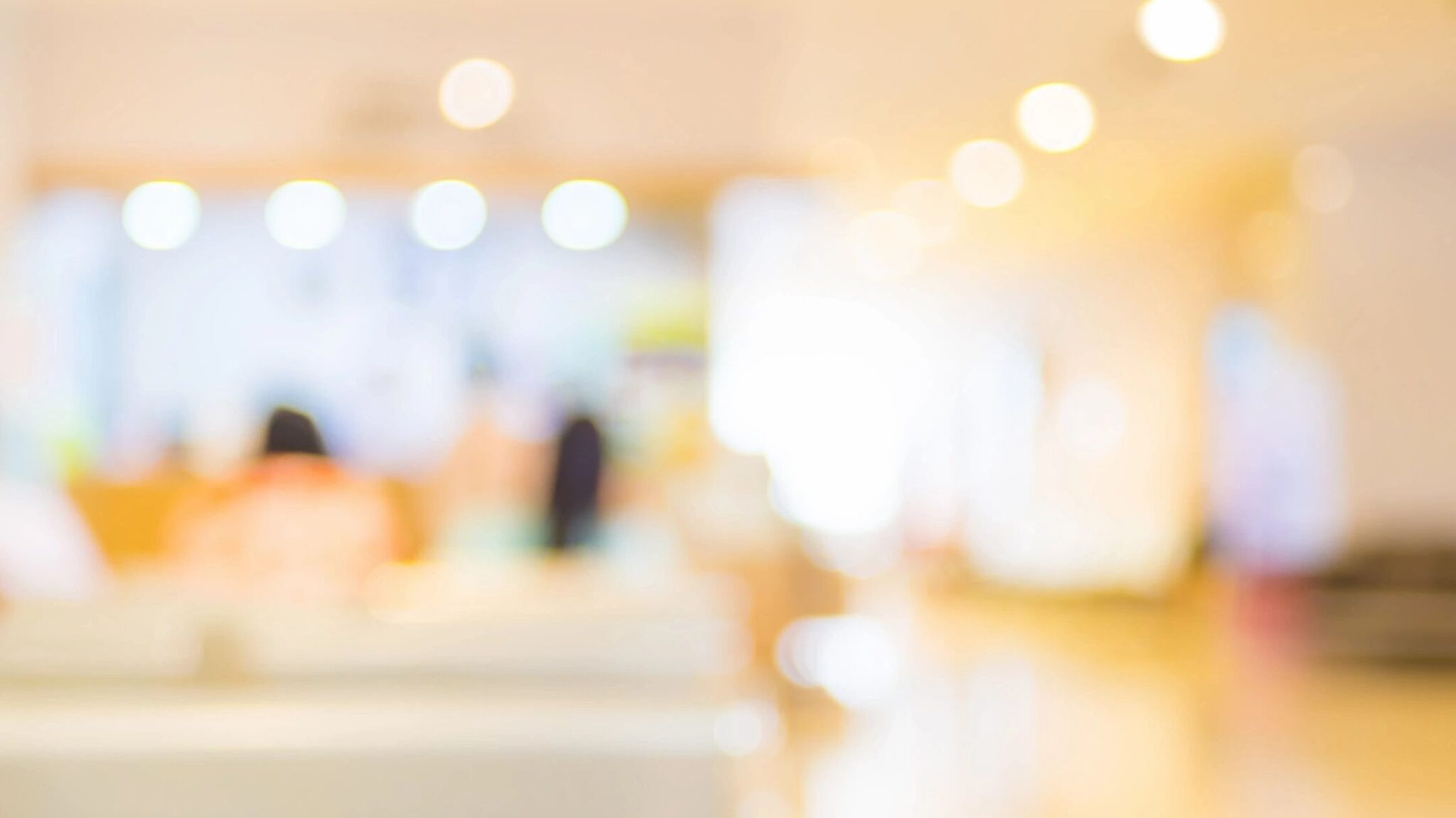 A blurry view of a mall's brightly lit food court.